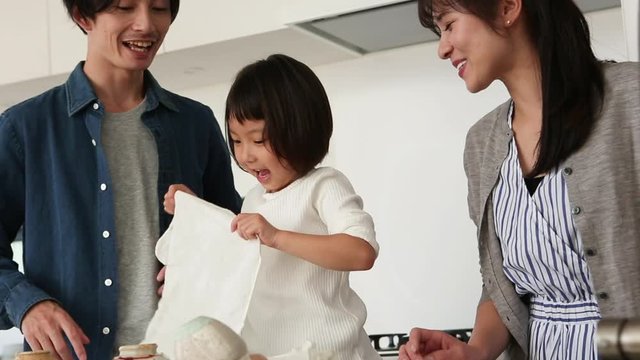 Parents cheering at little daughter folding piece of cloth