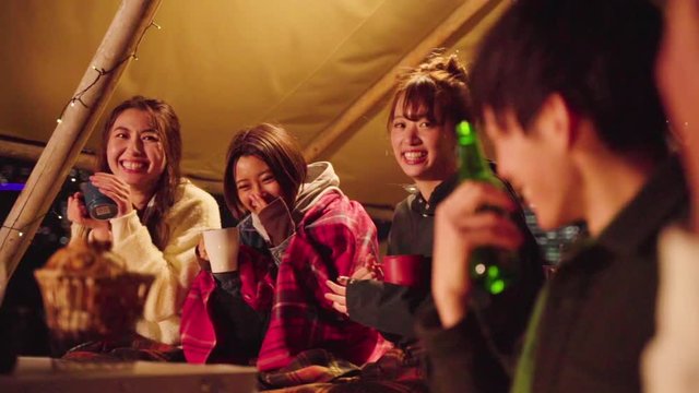 Group of friends talking while camping in tent at night