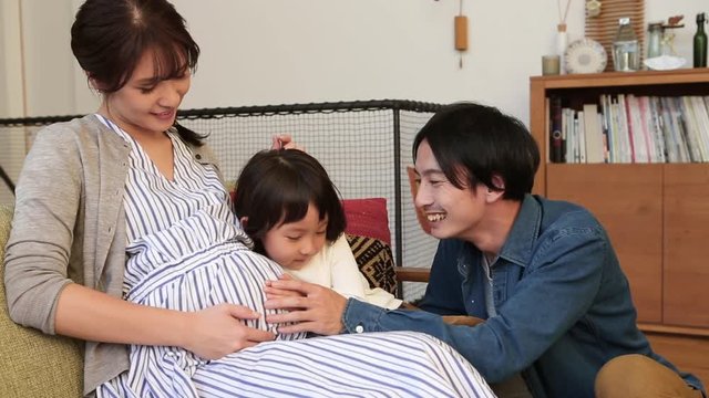 Close up of father and child touching pregnant mother belly