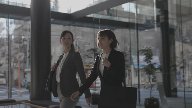 Tracking shot of young women walking out of office building