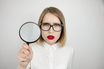 young beautiful blond woman holding magnifier near her face isolated white background