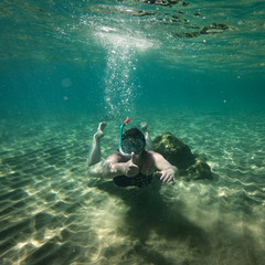 Underwater background with a diving woman in the ocean water. At the bottom of the sea.