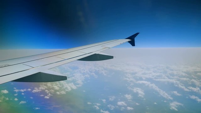 Aeroplane. View of airplane wing of aircraft flying above the clouds. 4K