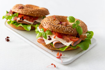 Homemade bagels with ham, cheese and tomatoes and salad on white background. Copy space