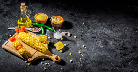 Fototapeta na wymiar Fresh yellow maize. Raw organic sweet corn cobs on black table. Top view with copy space