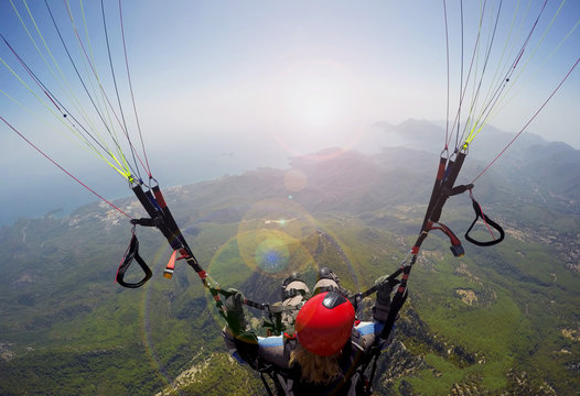 Paragliding in the sky. Woman girl is soaring in the sky on paraplane above mountains ans sea 