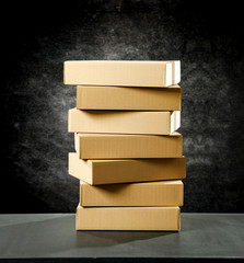 Boxes in a pile on a table top on a black wall background. Some parcel to send.