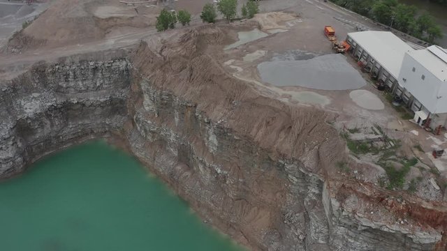 Drone flies over a quarry in the Midwestern USA and looks down on cool dirt formations.  in summer, in 4K.