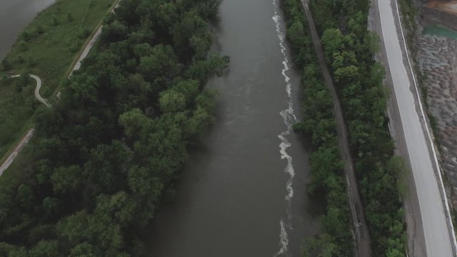 Drone flies over a Midwestern USA river, camera pans up to reveal a highway in the distance.  in summer, in 4K.