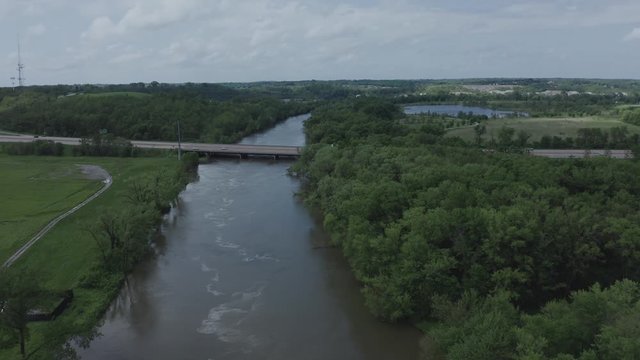 Drone flies over a river toward a lone highway in the Midwestern USA.  in summer, in 4K.