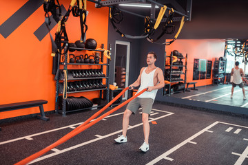 Nice sportive young man holding orange ropes