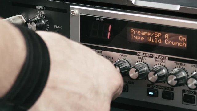 Musician's hand sets up levels of a guitar preamp multi effect.