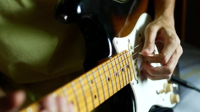 Lefthander playing electric guitar by holding pick by left hand.