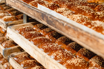 Wooden shelves with fresh pastries in a bakery. Sesame Buns.
