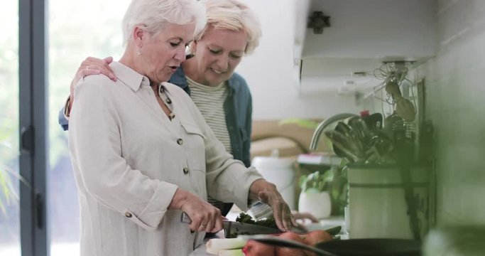 Mature lesbian couple cooking a meal together at home