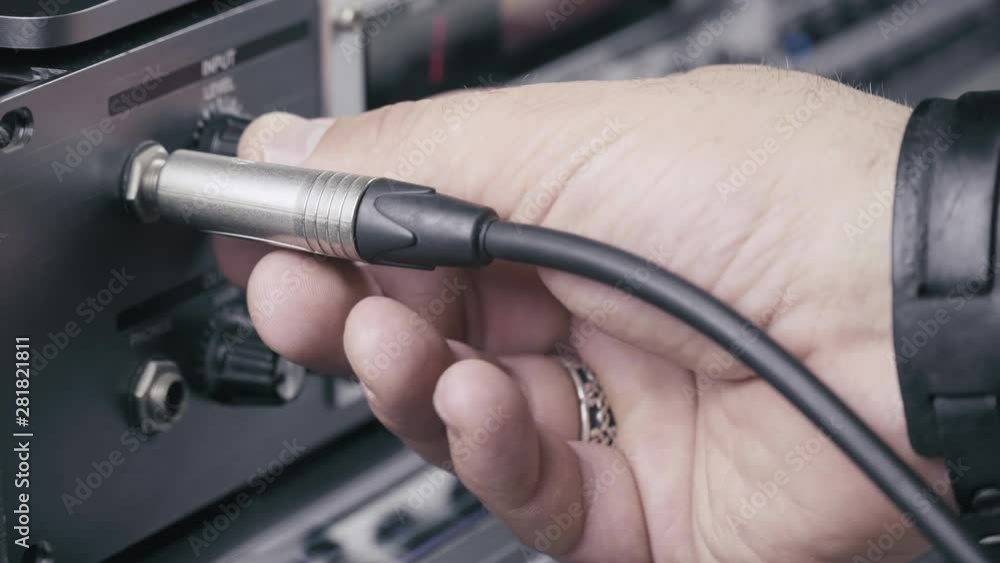 Poster musician plugs in the jack cable into a multi effect and sets up the input level at maximum, 4k.