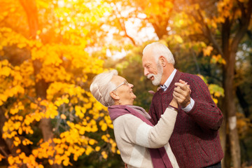Old senior couple dancing in nature.