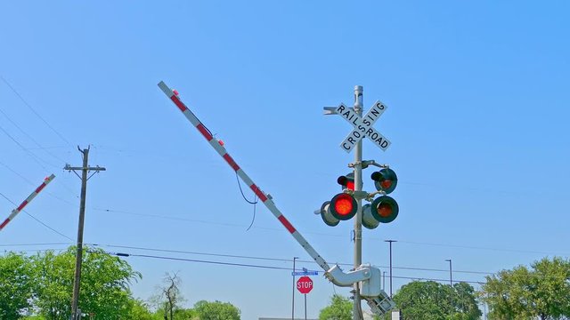 Rail road crossing with red lights flashing and barriers coming down Camera pulling back