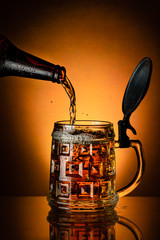 fresh beer poured from the bottle into the glass mug on the golden background