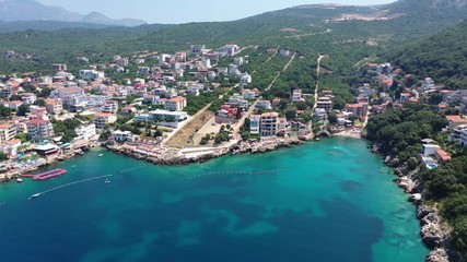 Flying from sea to the beach. Water in the sea is turquoise, clean and clear. Drone flies to the stone sea beach with its multicolored umbrellas and beach loungers. White boats near the shore