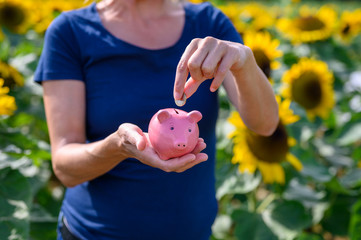 Frau steckt Euromünze in Sparschwein