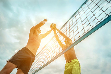 Beach Volleyball players in sunglasses in action with ball under