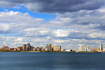 Fototapeta premium beautiful view of the city with skyscrapers on the background of the river with blue sky and storm clouds