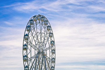 amusement ride ferris wheel on the background a blue sky with snow-white clouds