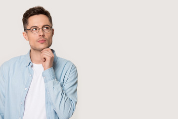 Pensive thoughtful young man pose on grey background looking aside