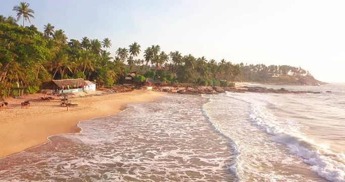 Ocean waves at sunset. Sri Lanka. Beautiful tropical beach with palm.