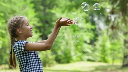 Girl playing with soap bubbles outdoor.