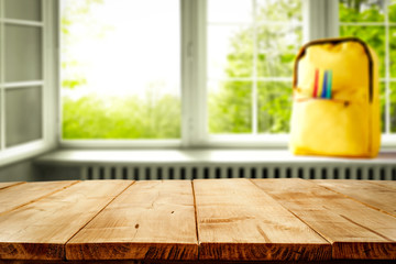 Wooden table desk with a window and yellow schoolbag. Empty space for you decoration and products.