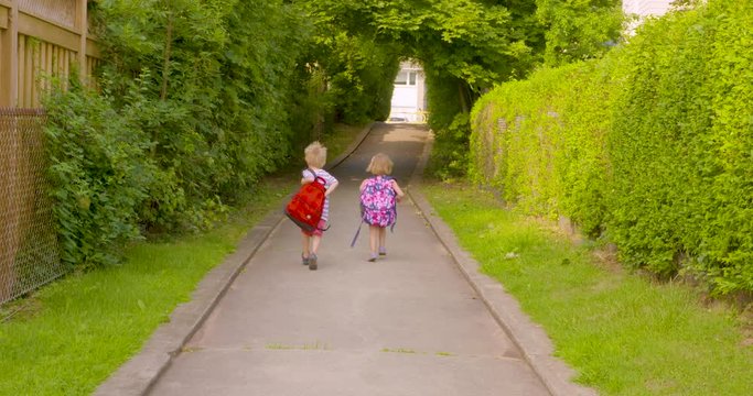 Two excited little kids run off to school together, then turn back to wave goodbye