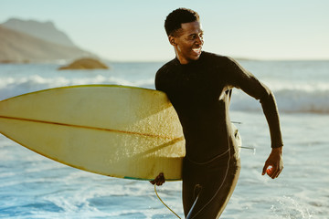 Smiling african male surfer - obrazy, fototapety, plakaty