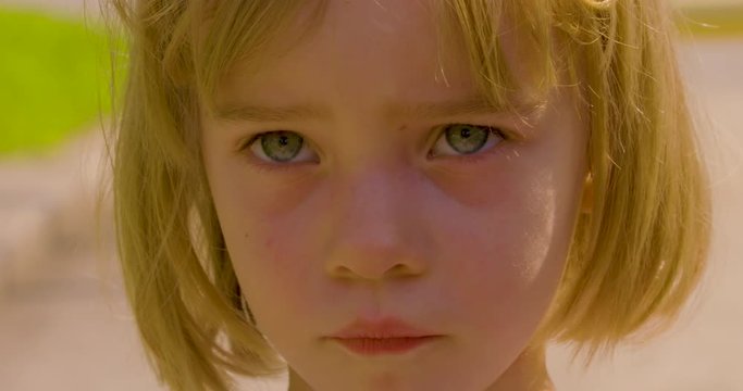 Sunlit portrait of a cute little girl acting sad
