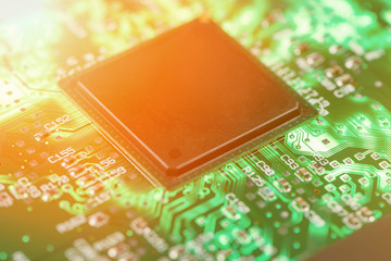 Backlit green printed circuit board with the processor is burning orange, background texture