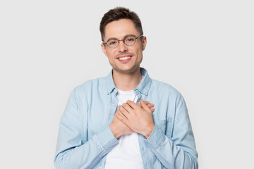 Young man in glasses holds hands on chest feels gratitude