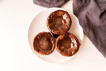 fresh homemade chocolate muffins with topping on white plate top view