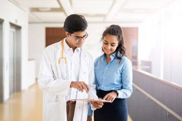 Arzt im Krankenhaus zeigt einer jungen Frau etwas auf seinem Klemmbrett