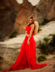 Young beautiful woman in red dress looking to mountains sea