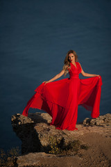 Naklejka premium Young beautiful woman in red dress looking to mountains sea
