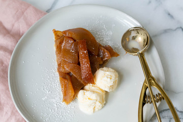 Slice of Caramel Apple Pie Tart with Vanilla Ice Cream, White Marble Background, Pink Napkin, Fork, Honey crisp Dessert