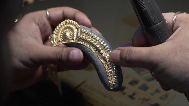 Professional goldsmith examining gold jewellery in wax mold intensely, close up