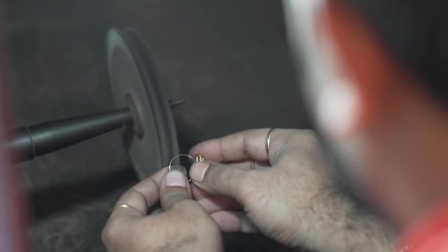 A man using a machine in a jewelry workshop for sanding a ring