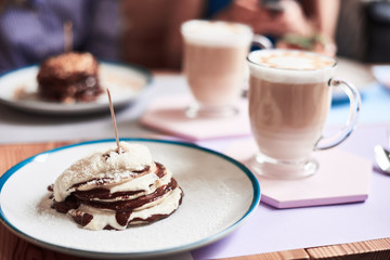 Cup of latte coffee with art milk foam on pink and violet board at morning. sweet pancake bounty with chocolate and coconut