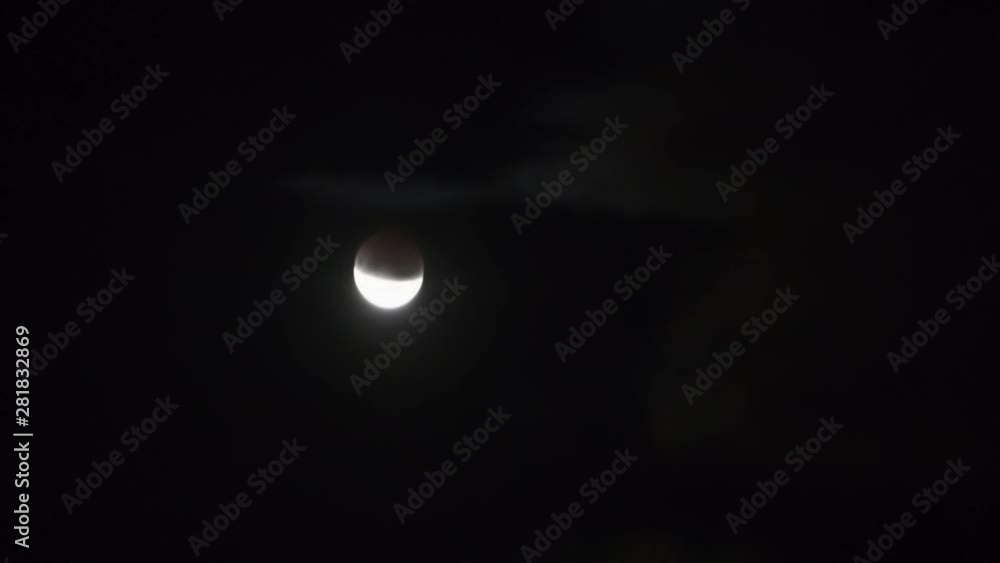 Wall mural moon moving on dark night sky with clouds during partial eclipse. full hd clip