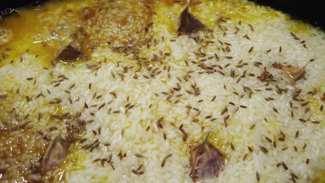Cooking of boiling traditional asian pilau with lamb meat, garlic  and rice. 4K clip