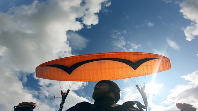 Paragliding activity in sky. Male paraglider is moving against the sky with the vehicle