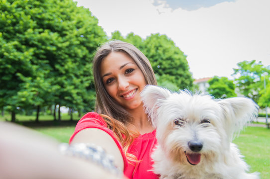 Pretty young woman doing selfie with her dog at the park