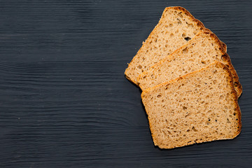 Freshly baked bread on a cutting Board. Black wooden background.